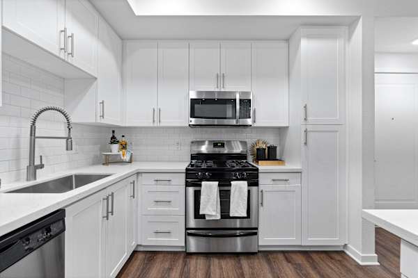 a white kitchen with stainless steel appliances and white cabinets